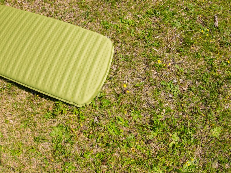 Matelas gonflable vert posé sur l'herbe