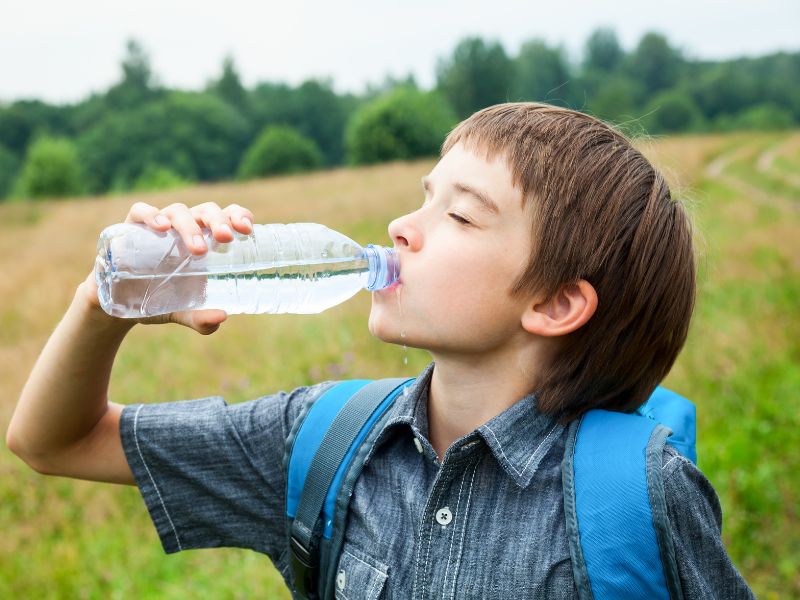 Petit garçon qui boit de l'eau en randonnée