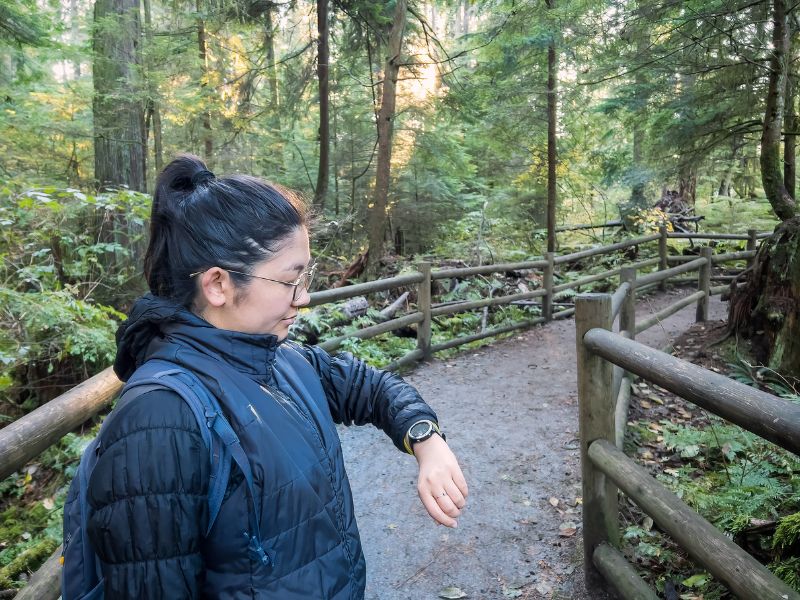 Femme qui consulte sa montre de randonnée dans la forêt