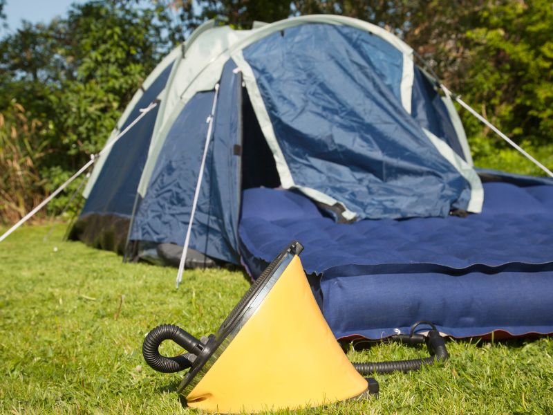 Pompe pour matelas de camping devant une tente