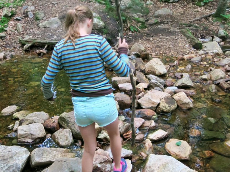 Fille qui marche sur des rochers au-dessus d'une rivière